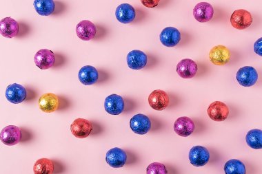 Pembe bir arka plan üzerinde renkli şeker yaratıcı düzeni. En az tatil kavramı.