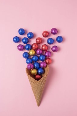 Dondurma külahı pembe bir arka plan üzerinde renkli candyes ile. En az tatil kavramı.