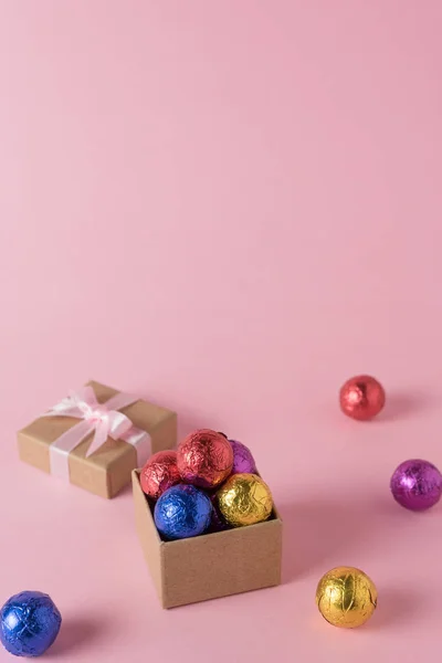 Creative layout of colored candy and gift box on pink background. Minimal holiday concept.