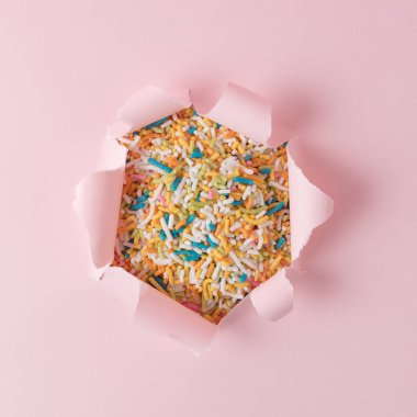 Canlı pembe yırtık kağıt ile renkli arka plan sprinkles. En az soyut kavram.