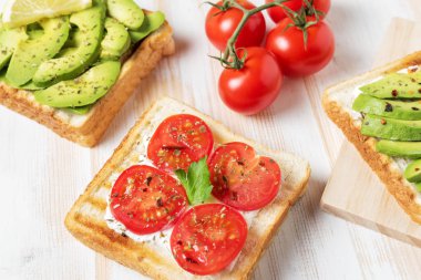 Tost ekmeği ile baharat beyaz ahşap zemin üzerinde üzerinde avokado dilimlenmiş.