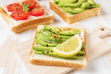 Tost ekmeği ile baharat beyaz ahşap zemin üzerinde üzerinde avokado dilimlenmiş. 