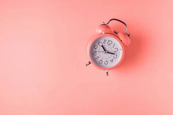 Reloj despertador de color coral sobre fondo brillante. Concepto mínimo . — Foto de Stock