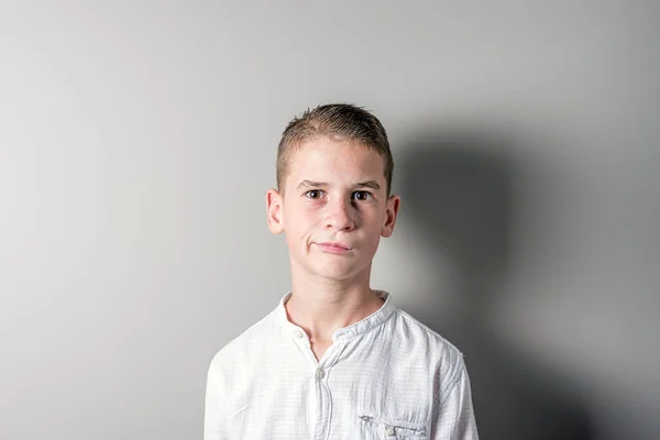 Aranyos fiú világos háttéren fehér ing gondolkodás. — Stock Fotó