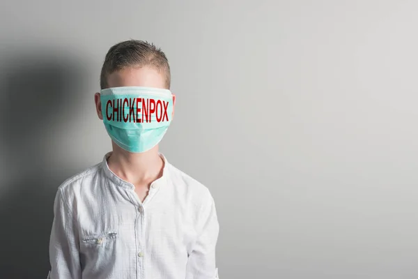 Niño con una máscara médica con inscripción roja CHICKENPOX en su fac — Foto de Stock