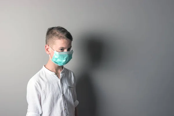 Ragazzino, un bambino con una maschera medica su uno sfondo brillante. Th — Foto Stock