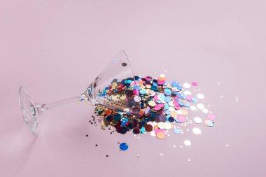 Martini kadehi ile pembe bir arka plan üzerinde renkli pırıltılar. Yaratıcı en az parti konsept. 