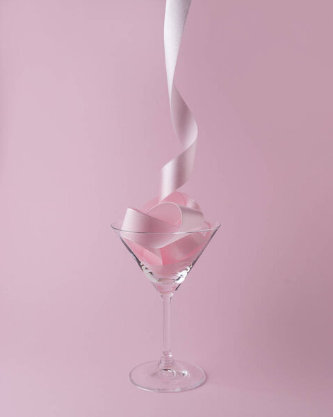Martini glass with pink party ribbon. Minimal celebration concept.