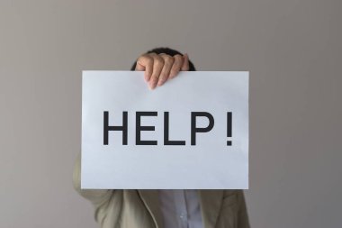 Bir kadın onun önünde yardım yazıt ile bir afiş tutar.