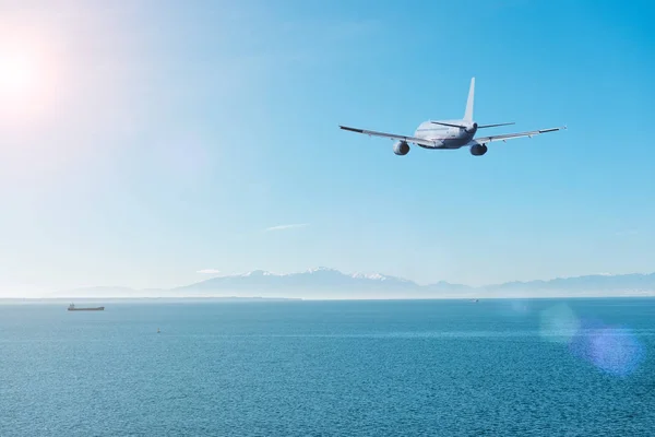 Vliegtuig vliegen over de zee en de bergen. Travel concept. — Stockfoto