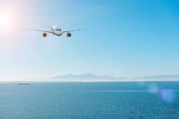 Deniz ve dağlar üzerinde uçan uçak. Seyahat kavramı. — Stok fotoğraf