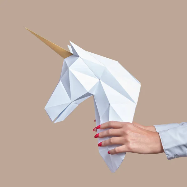 Las manos sostienen un modelo de papel blanco 3d de Unicornio. Concepto de arte mínimo . — Foto de Stock