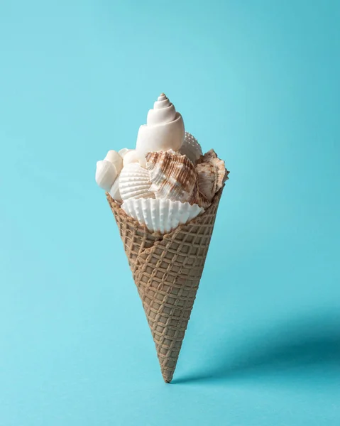 Tvůrčí kompozice s mušlemi a kužel zmrzliny na pastelově modré pozadí. Letní minimální koncept. — Stock fotografie