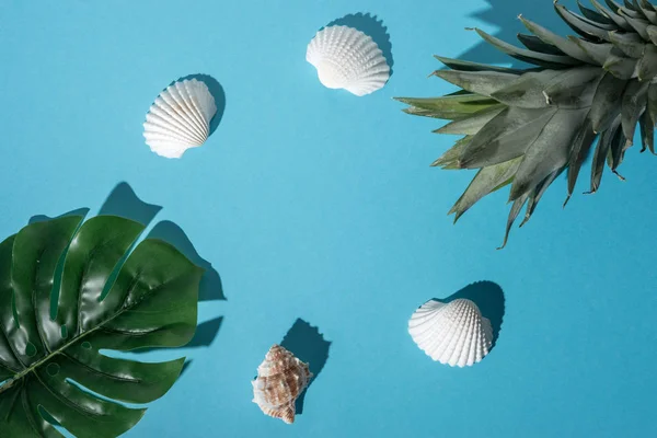 Composizione creativa con conchiglie, foglia di palma tropicale e ananas su sfondo blu pastello. Concetto estate minima . — Foto Stock