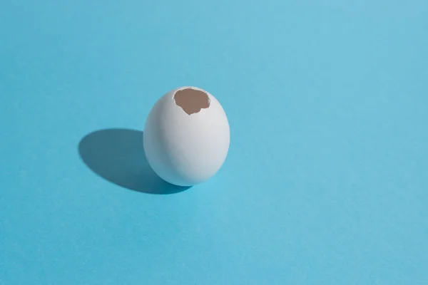 Cáscara de huevo blanco sobre fondo azul brillante. Concepto mínimo de Pascua . —  Fotos de Stock