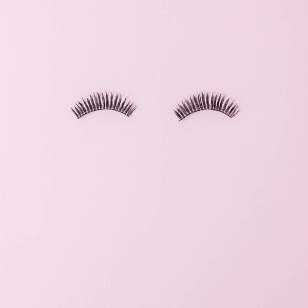 Eyelashes on pastel pink background. Summer minimal concept.