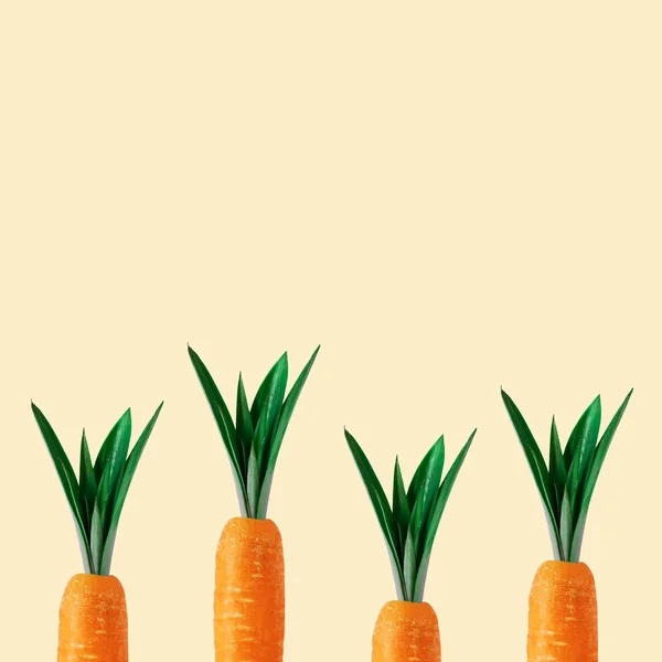 Морква з ананасовим листям на пастельно-жовтому тлі. Мінімальна весняна композиція . — стокове фото