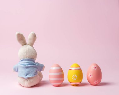 Renkli Paskalya yumurtaları ile beyaz tavşan bebek. Minimal Paskalya konsepti.