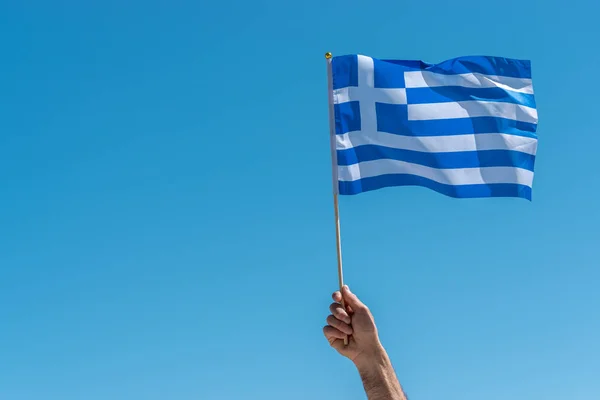 Gökyüzü arka planda insan elinde Yunanistan bayrağı.