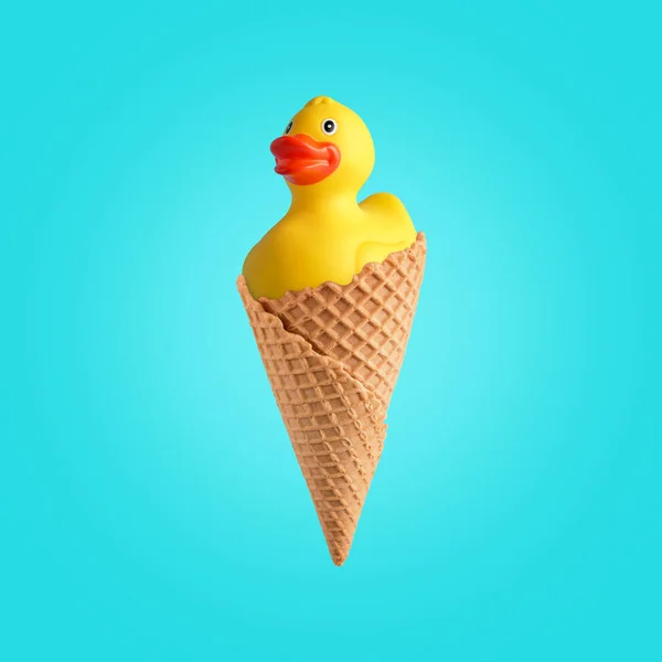 Žlutá gumová kachna s kuželem zmrzliny na jasném pozadí. Letní minimální koncept. — Stock fotografie