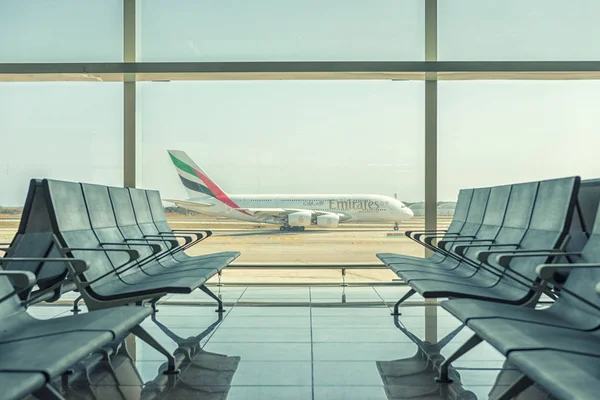 Барселона, Испания - 17 марта 2019 года: пустые кресла в лофте вылета в аэропорту на фоне взлетающего самолета. Концепция путешествия . — стоковое фото