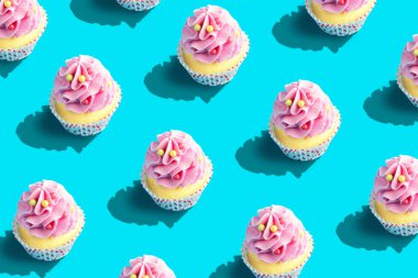 Pastel mavi arka plan üzerinde renkli cupcake desen. Yaratıcı minimal parti konsepti.