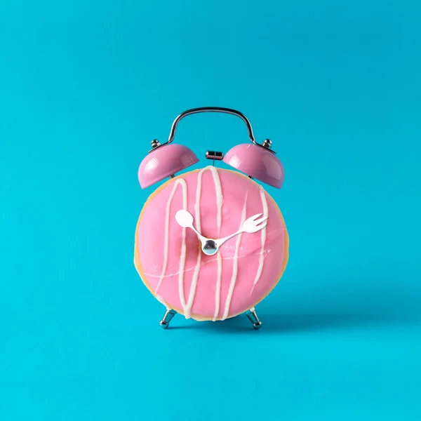 Pastel mavi arka plan pembe çalar saat donut. Minimal konsept — Stok fotoğraf