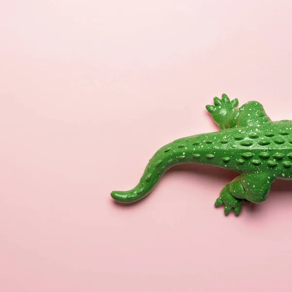 Schwanz aus grünem Krokodilspielzeug auf pastellrosa Hintergrund. Minimales Kunstkonzept. — Stockfoto