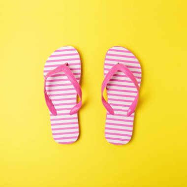 Sarı arka planda plaj terlik leri ile yaratıcı kompozisyon. Yaz minimal kavramı.