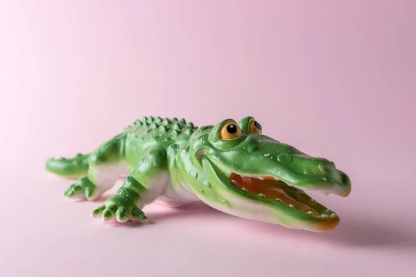 Grünes Krokodilspielzeug auf pastellrosa Hintergrund. Minimales Kunstkonzept. — Stockfoto