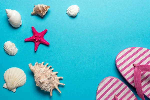 Composizione creativa con conchiglie e ciabatte da spiaggia su sfondo blu. Concetto estate minima . — Foto Stock