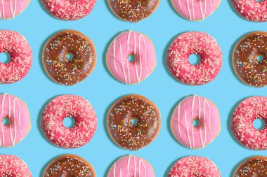 Pastel mavi arka plan üzerinde renkli donut deseni. Yaratıcı minimal yaz konsepti.