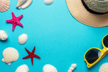 Deniz kabukları, şapka ve mavi arka plan üzerinde sarı güneş gözlüğü ile yaratıcı kompozisyon. Yaz minimal kavramı.