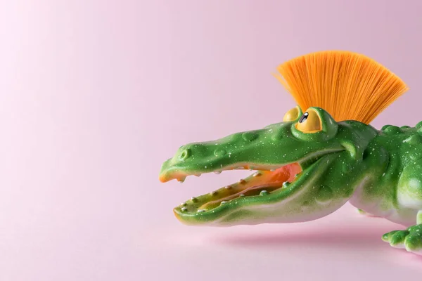 Grünes Krokodilspielzeug mit Mohawk auf pastellrosa Hintergrund. Minimales Kunstkonzept. — Stockfoto