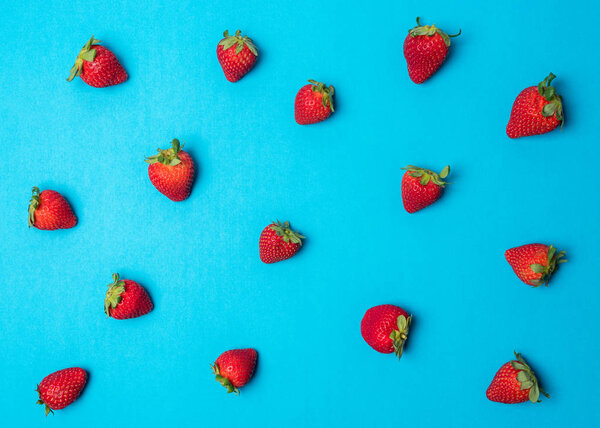 Colorful pattern made of strawberries on bright blue background. Minimal summer concept.