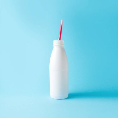 Parlak mavi arka planda saman ile beyaz şişe. Minimal yaz içeceği konsepti.