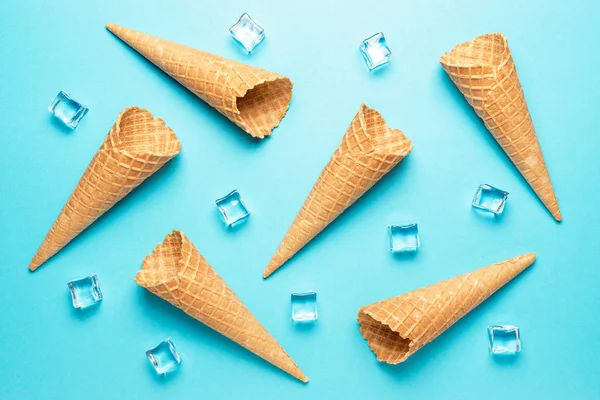 Varios conos de helado con cubitos de hielo sobre fondo azul.Concepto mínimo de verano . — Foto de Stock