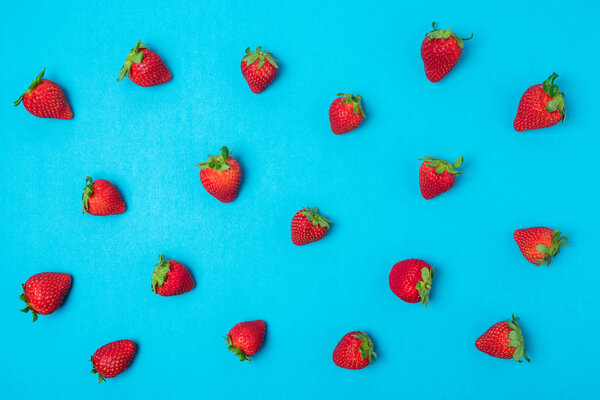 Colorful pattern made of strawberries on bright blue background. Minimal summer concept.