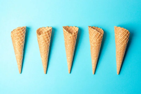 Varios conos de helado sobre fondo azul. Concepto de verano mínimo . — Foto de Stock