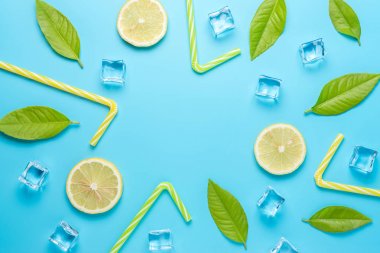 Mavi arka planda dilimlenmiş limon, saman ve buz küpleri ile yaratıcı yaz kompozisyon. Minimal içecek konsepti.