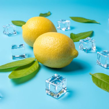 Mavi arka planda limon ve buz küpleri ile yaratıcı yaz kompozisyon. Minimal içecek konsepti.