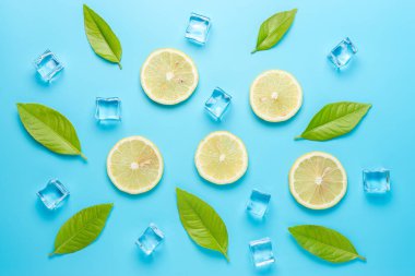 Mavi arka plan üzerinde dilimlenmiş limon ve buz küpleri ile Yaratıcı yaz kompozisyon. Minimal içecek konsepti.
