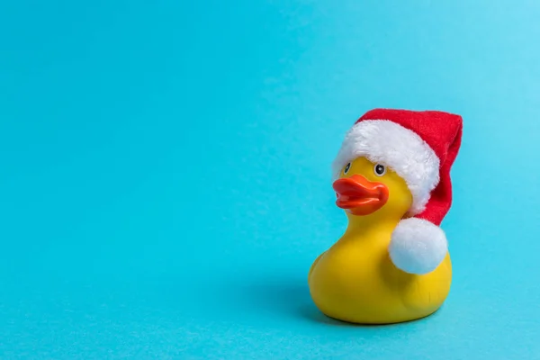 Mavi arka planda Santa şapka ile kauçuk ördek. Minimal Noel veya yeni yıl konsepti.