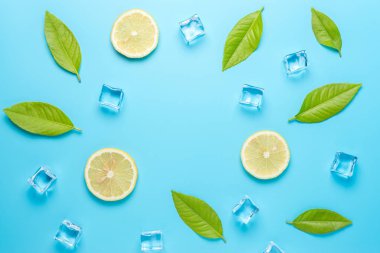 Mavi arka plan üzerinde dilimlenmiş limon ve buz küpleri ile Yaratıcı yaz kompozisyon. Minimal içecek konsepti.