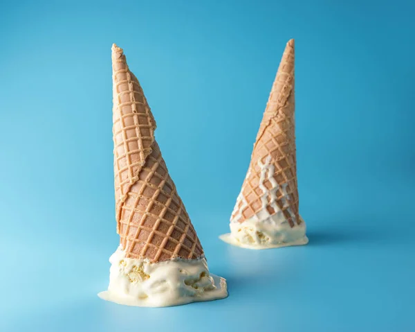 Dos helados derretidos con conos de helado sobre fondo azul pastel. Concepto mínimo de comida de verano . — Foto de Stock