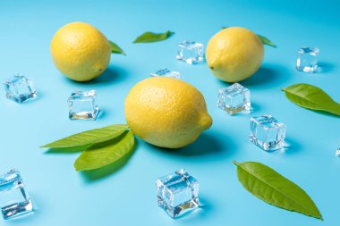 Mavi arka planda limon ve buz küpleri ile yaratıcı yaz kompozisyon. Minimal içecek konsepti.