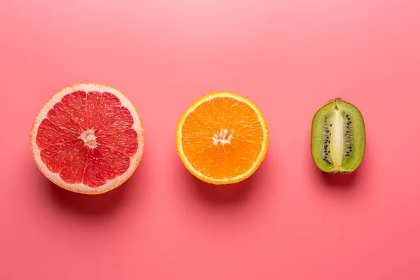 Creative fruit composition on pink background with hard shadows.