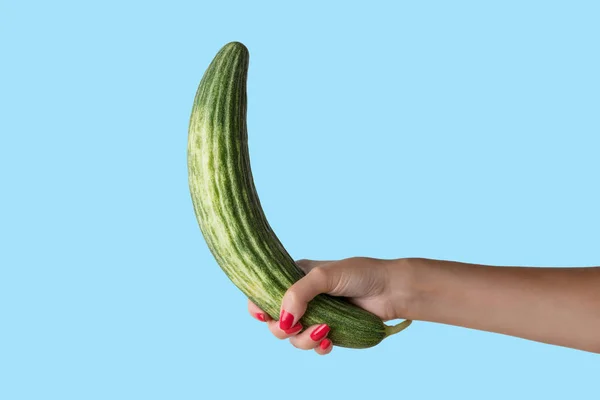 Women hand holding cucumber like a man's penis on blue background. — Stock Photo, Image