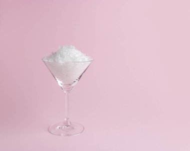 Pastel pembe arka planda martini cam kar. Minimal Noel veya yeni yıl konsepti.