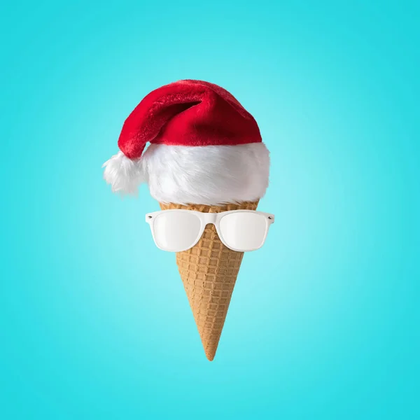 Mavi arka planda dondurma koni ile Noel Baba beyaz güneş gözlüğü ve şapka. Yeni yıl veya Noel minimal kavramı.